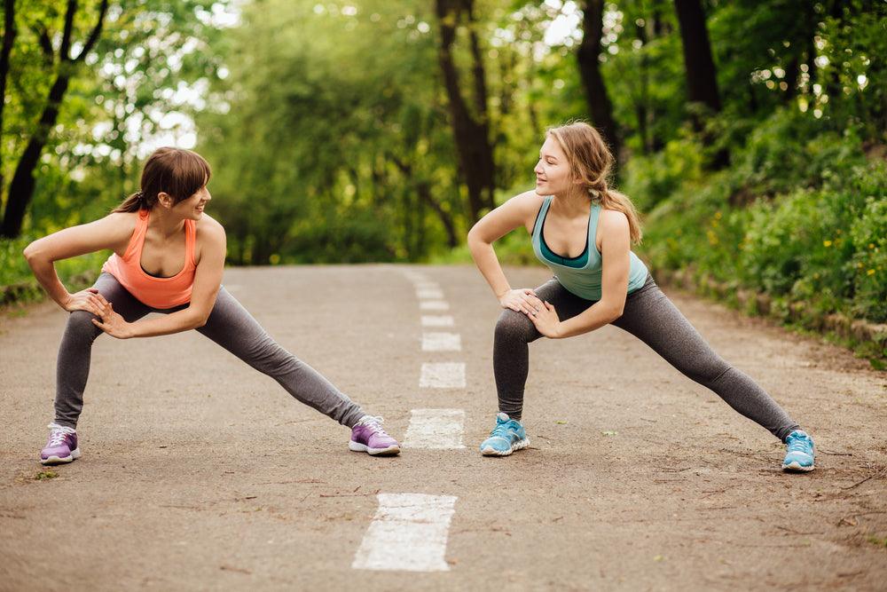 two women stretching and wearing compression leggings to alleviate swollen legs