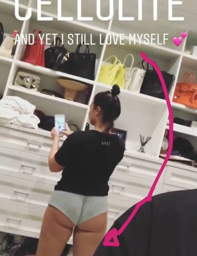 Woman taking a mirror selfie in underwear with visible cellulite, standing confidently in front of a closet. Text overlay reads "CELLULITE AND YET, I STILL LOVE MYSELF" with a pink heart.