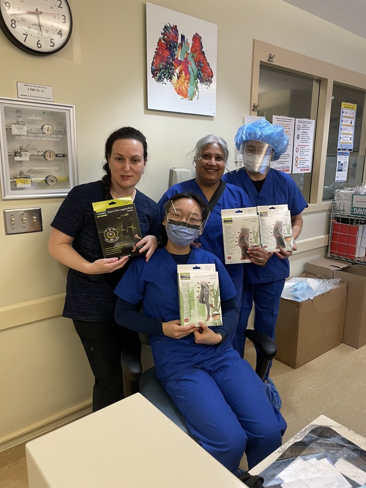 "Four nurses in hospital uniforms smiling and holding Mass & Slim compression leggings by TheBlackPurple, showcasing support for wellness and circulation during long shifts.